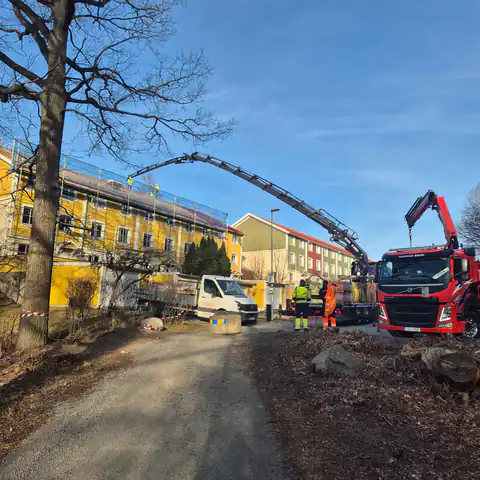 Kranbilar levererar takmaterial till huset i Huddinge