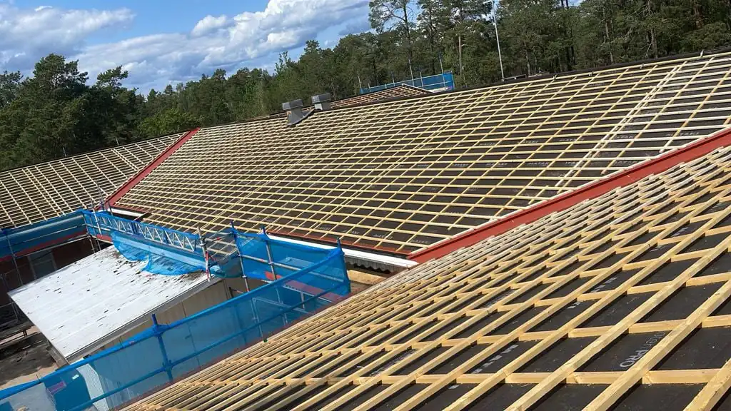 Läktat tak före pannläggning, med ny takfotsplåt och ställning runt huset