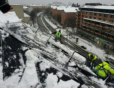Takskottning på ett flerbostadshus i Stockholm, med avspärrad gata nedanför